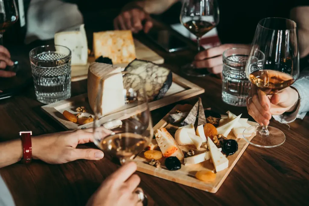 People around a table with cheese platters and wine glasses