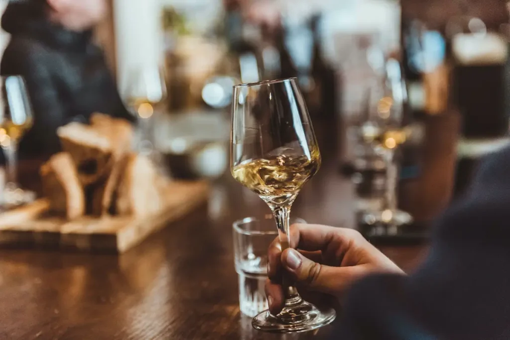 People sitting around a table with glasses of white wine. The main focus is on a hand swirling a wine glass