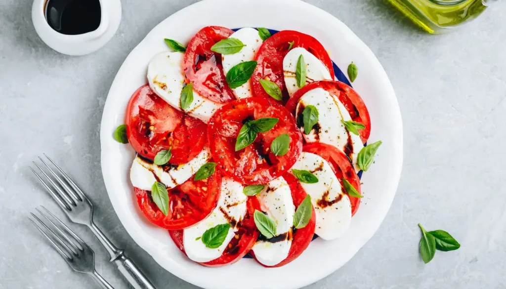 A Caprese salad in a plate with ripe tomatoes, mozzarella, basil and balsamic vinegar