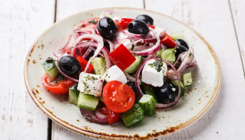 A Greek salad with tomatoes, onions, cucumber, olives and feta