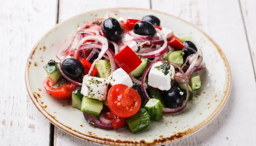 A Greek salad in a plate, with feta cheese, cucumbers, cherry tomatoes, olives and onions