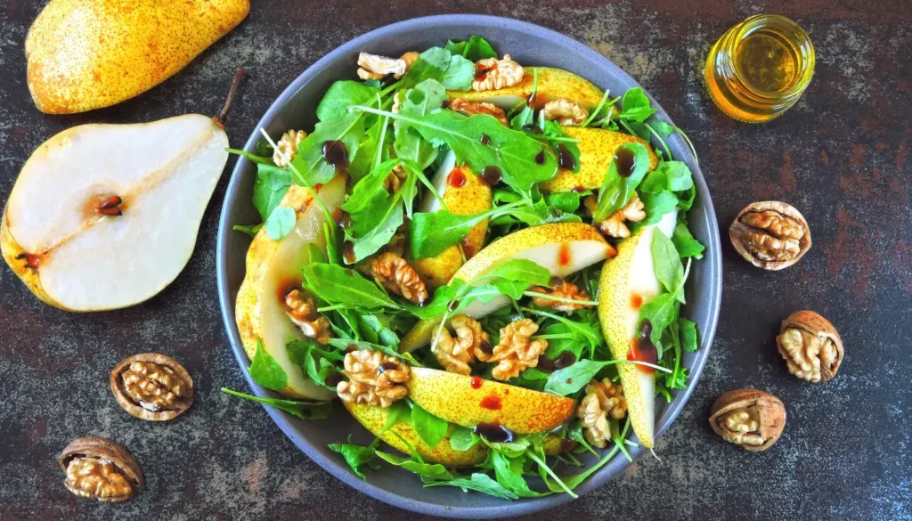 A rocket and pear salad in a bowl with walnuts and honey