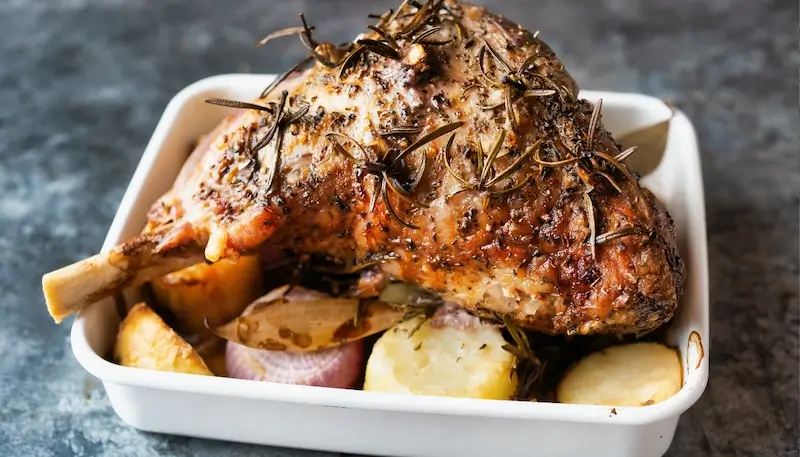 Roast leg of lamb in an oven dish with roasted vegetables