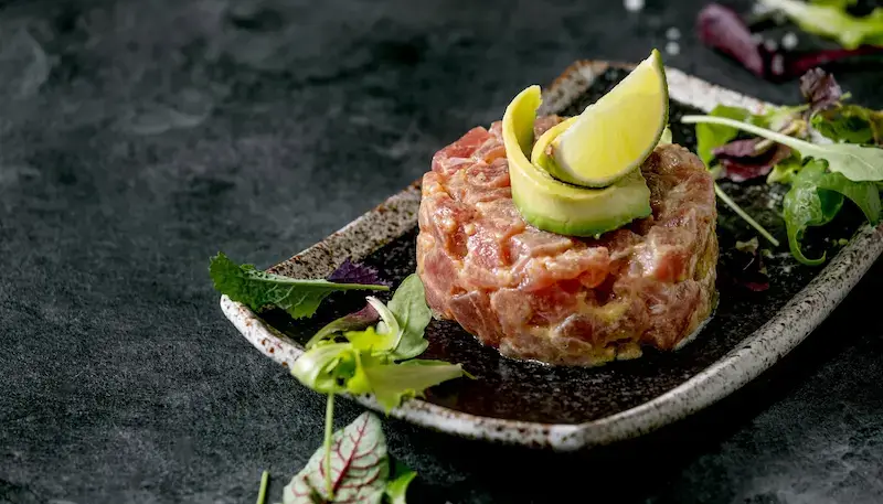 Tuna tartare in a plate with some salad and avocado