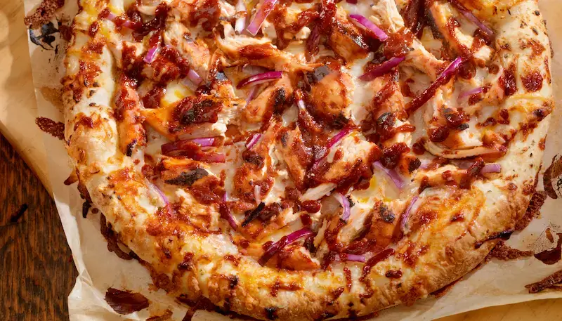 A BBQ chicken pizza with chicken, bbq sauce and red onions