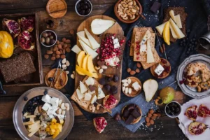 Table with cheese boards with nuts, crackers, pomegranate and grapes