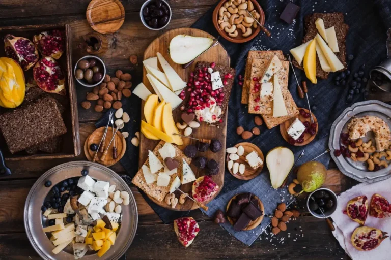 Table with cheese boards with nuts, crackers, pomegranate and grapes