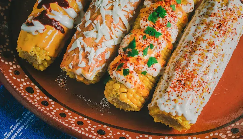 Mexican street corn (Elote) with different sauces and accompaniements