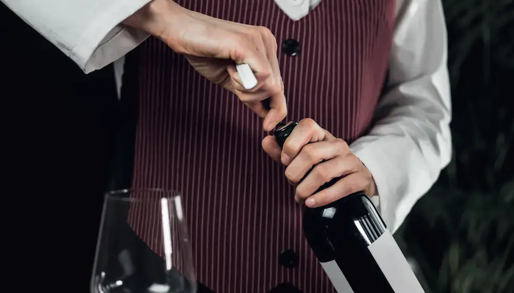 A waiter opening a wine bottle