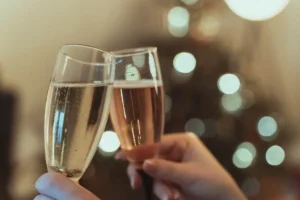 Two people cheering with a glass of Champagne and a glass of Prosecco