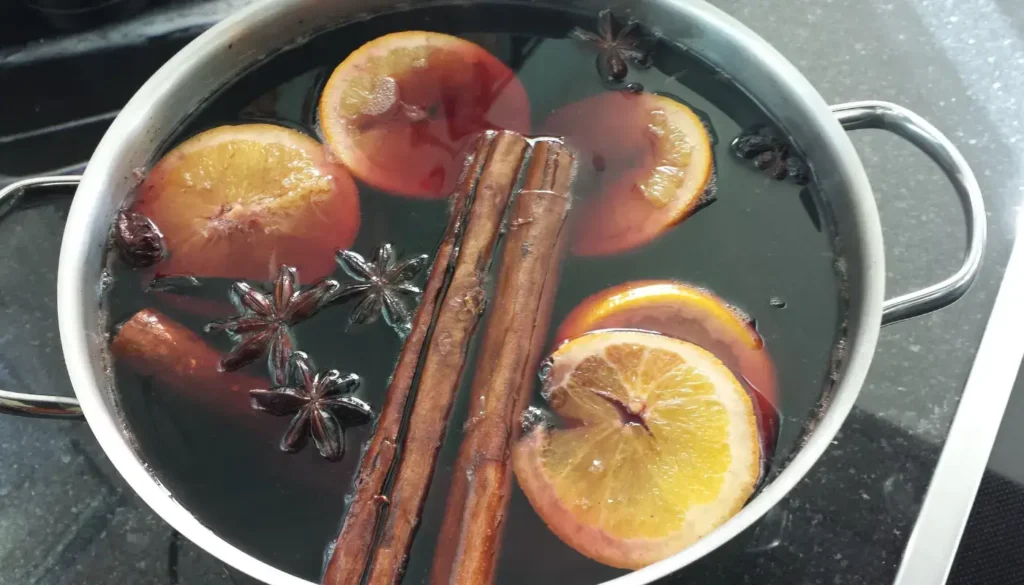 Mulled wine gently warming in a saucepan with spices and orange