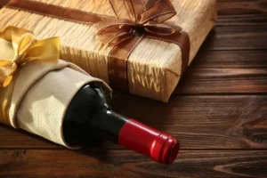 A bottle of wine wrapped as a gift with a ribbon