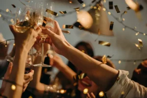 Glasses of Champagne clinking at a New Year's Eve party with confetti