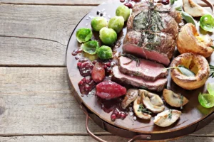 Sliced roast beef with Yorkshire puddings, Brussels sprouts and mushrooms on a wooden board