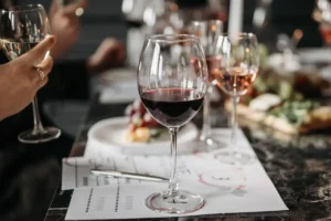 A wine tasting sheet with a pen, next to glasses of red, rosé and white wine